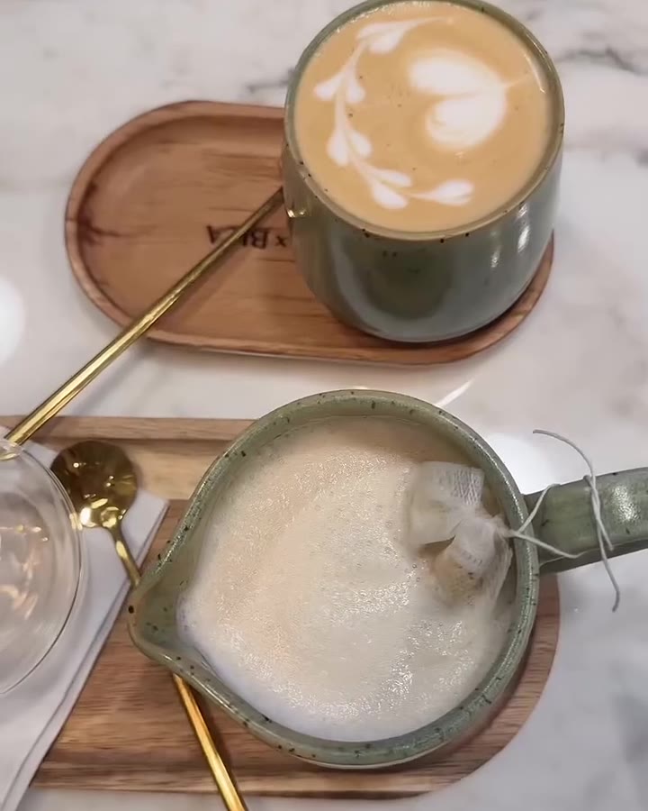 Latte art in a sage cup on a wooden tray at Café X Bica